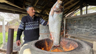 (ویدئو) نمایی نزدیک از نحوه پخت یک ماهی بزرگ در تنور توسط خانواده آذربایجانی
